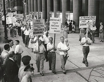 1955, August 15. HA. Chicago, Illinois. More than two dozen Ukrainian pickets march in front of Michigan Avenue office building where the members of the Russian farm delegation held a press conference. United Press Photo (Front)