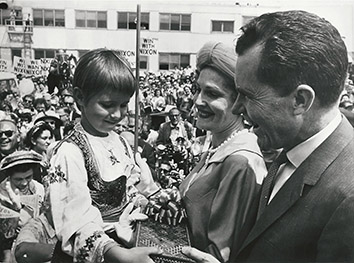 1960, July 25. BA. Chicago, Illinois. DISTINGUISHED VISITORS RECEIVE A PRESENT. Vice President Nixon and Mrs. Nixon receive a gift from girl in Ukrainian native attire at the Republican Convention. AP Wirephoto (Front)