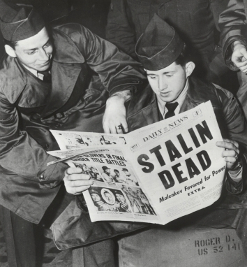 1953, March 5. BA. New York, New York. Two soldiers, waiting to board trains in Pennsylvania Station, late 3/5, read about the death of Russian Premier Josef Stalin and display different reactions. Alex Fenton (left) of Pittsburgh leans on Roger Green of East Liverpool, who holds the newspaper. UNITED PRESS (Front)