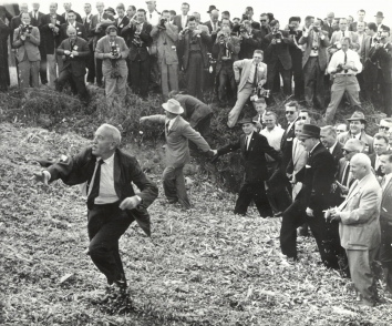 1959, October. JA. Coon Rapids, Iowa. BARNYARD FLING. Farmer Roswell Garst, host to Soviet Premier Khrushchev, right, hurled cornshucks at some of swarm of newsmen crowding around as he led the Russian leader ontour of his Iowa acres in Sept. 1959. Walking along with Khrushchev was Henry Cabot Lodge, dark suit and glasses, then U.S. Ambassador to the United Nations. AP Wirephoto. (Front)